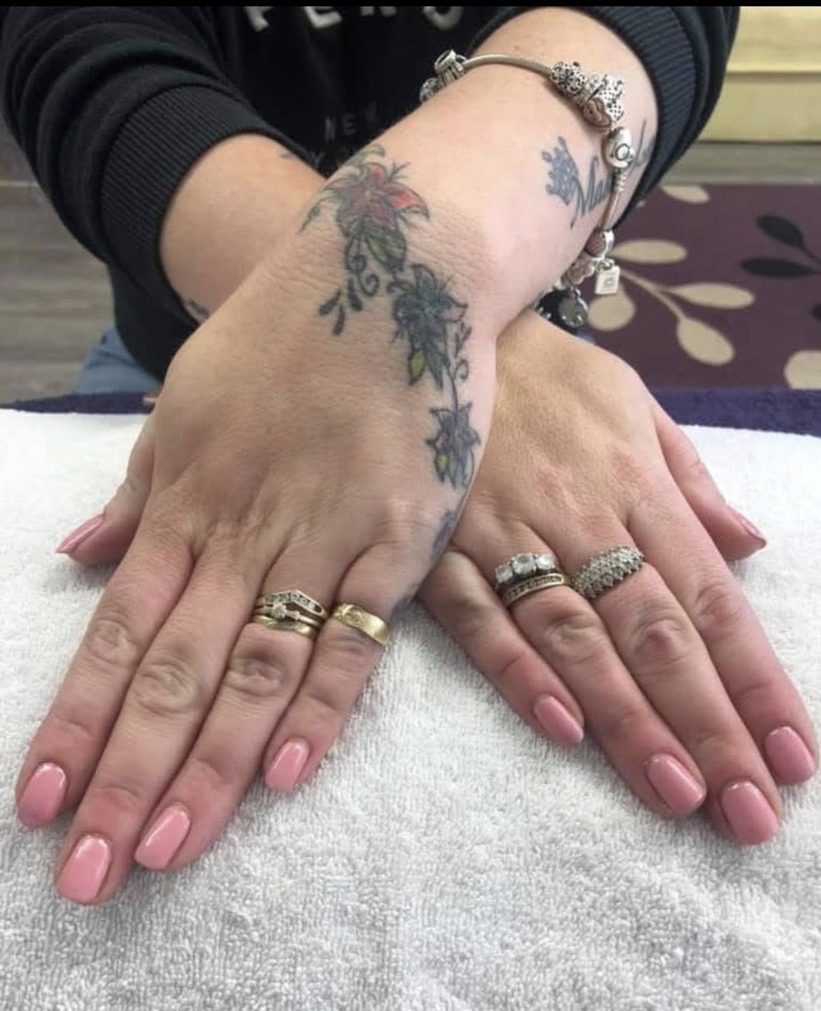 Hands stacked on a white towel with a deep plum gel manicure.